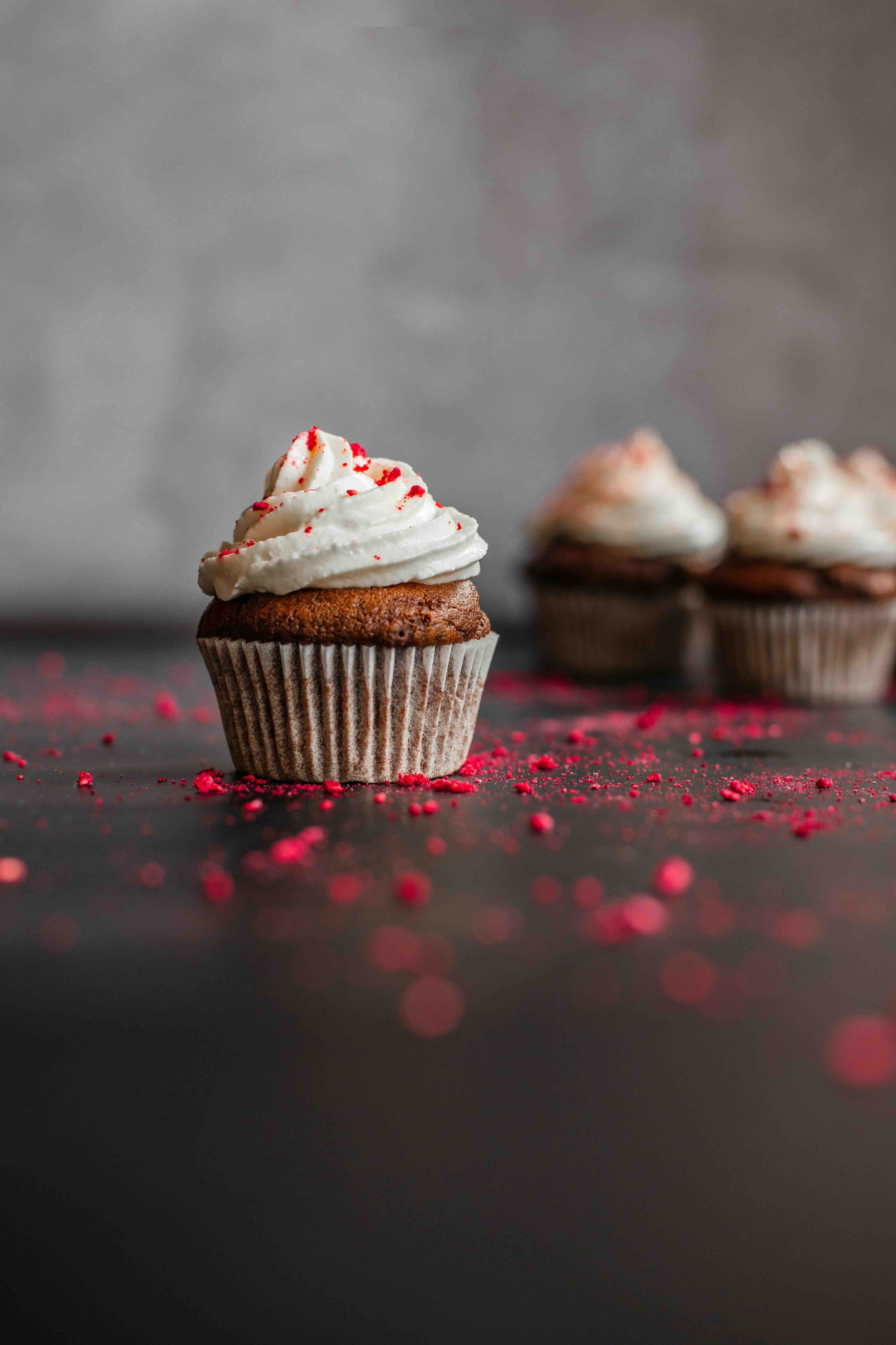 Chocolate cupcake topped with swirled frosting and raspberry crumbs